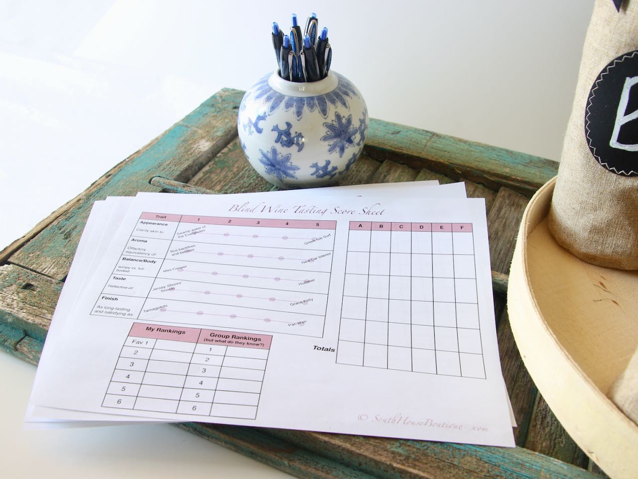 stack of pop-culture based scorecards for a blind wine tasting party shown with a jug of pens