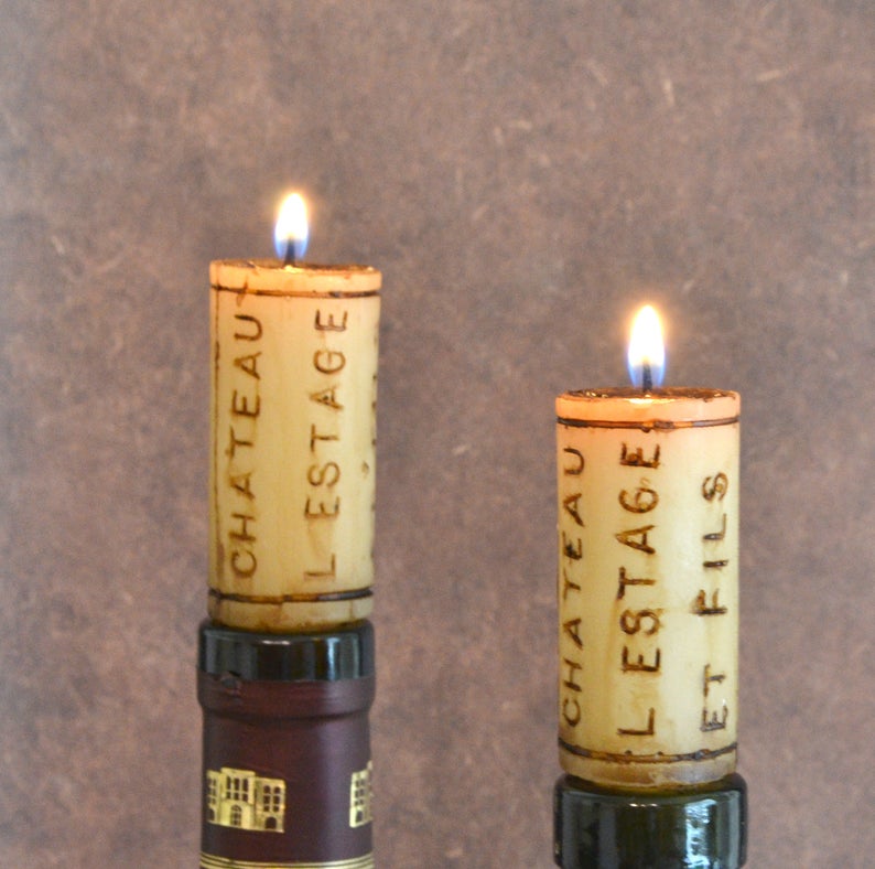 Two lit candles that look like corks in the top of two wine bottles