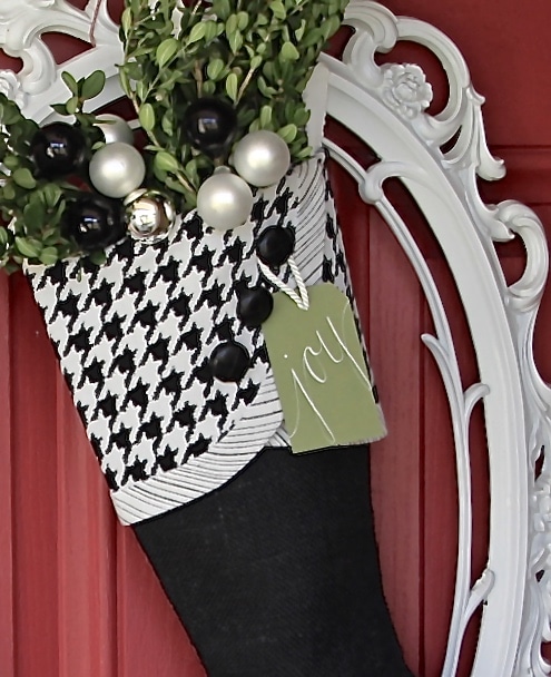 black and white christmas stocking hangin in a white frame on a red door