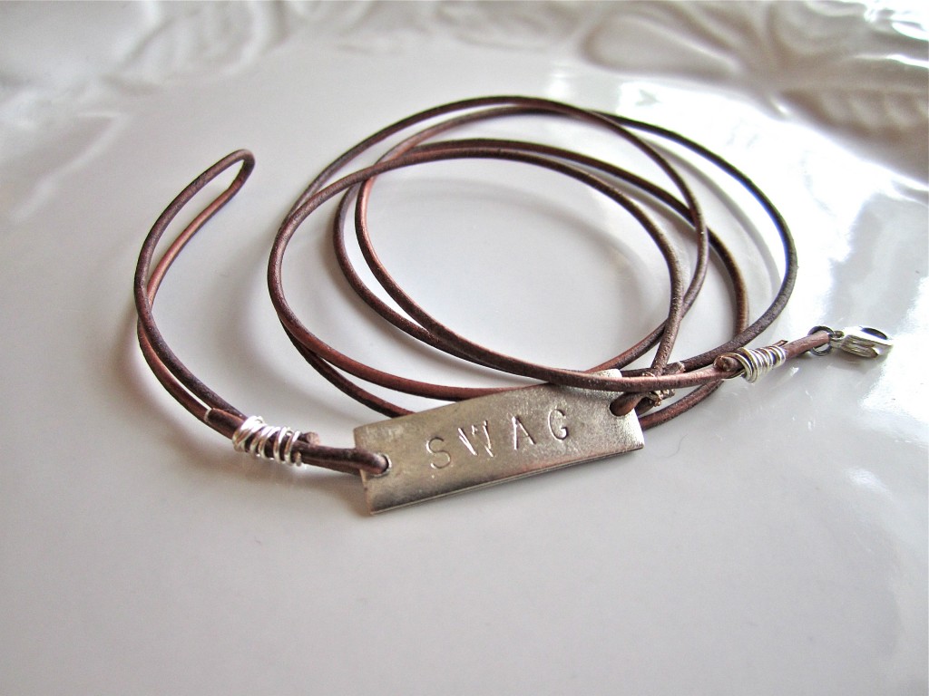 Finished leather and stamped metal bracelet on a white plate 