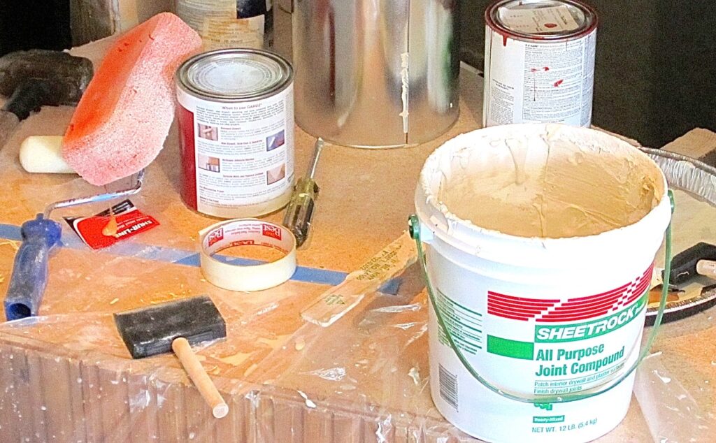 Bucket of joint compound, surplus latex paint, foam brush, sponge, etc. needed to create our faux concrete fireplace surround, mantel and tapered flue 