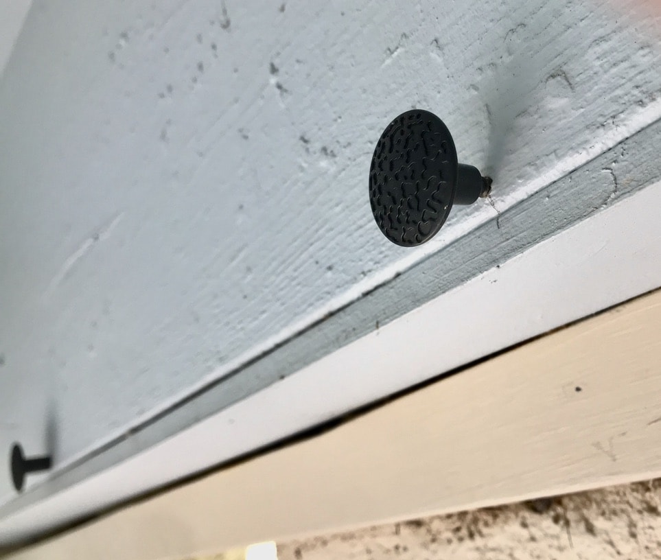 Closeup of black knob on dowel screw screwed into header
