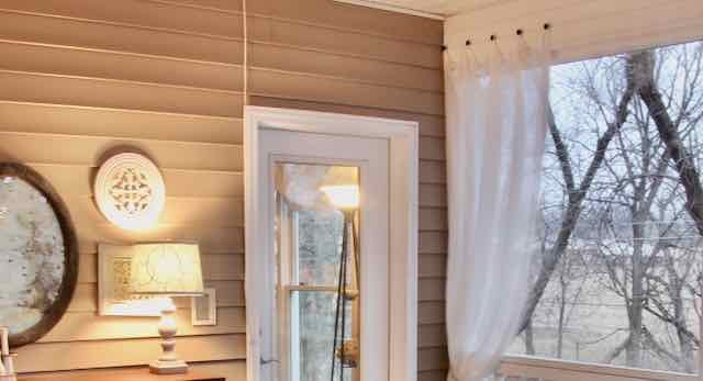 single sheer white curtain panel hanging on screened porch