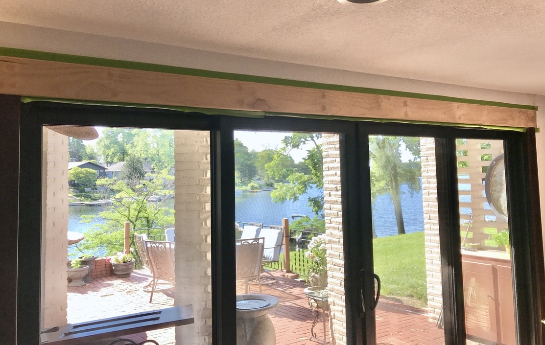 view out glass wall with red brick patio and lake in distance