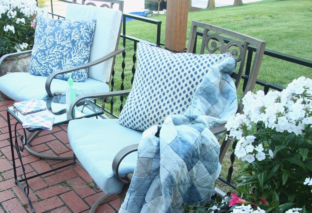 Two outdoor chairs made comfy with extra pillows and throws and a small table