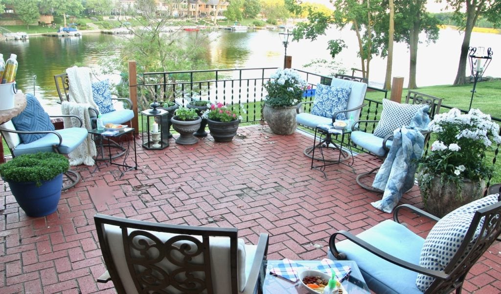 Three sets of two chairs and tables on brick patio overlooking lake