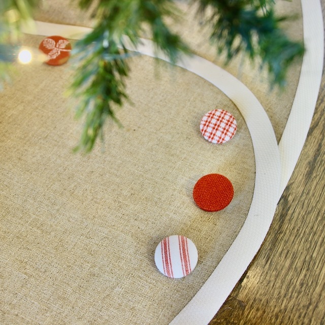 Closeup of Linen Christmas Tree Skirt Banded in Creamy White Banding and Red & White Buttons