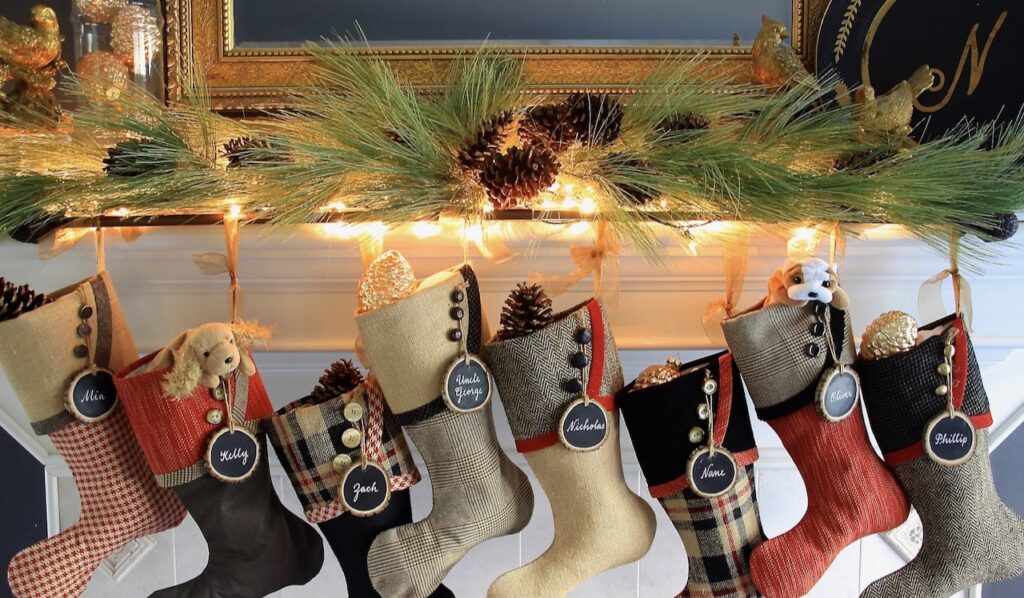 Set of 8 red, black and gold Christmas stockings hanging from a white mantel with brown stocking rod