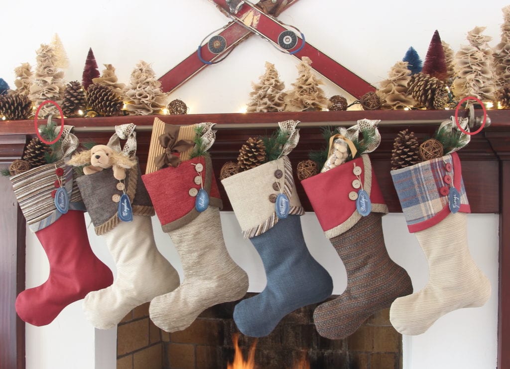Set of 6 red, blue and tan Christmas stockings hanging on from mantel with vintage skis and burlap and bottle brush trees