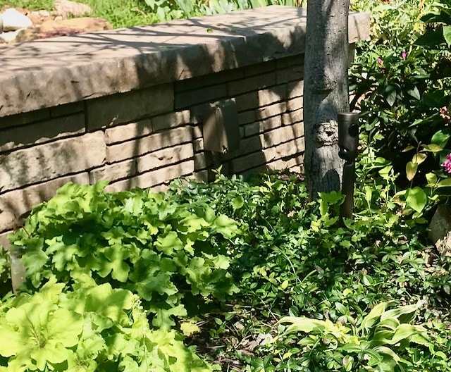 Landscape details: Painted camouflaged power box on a stone landscaping wall