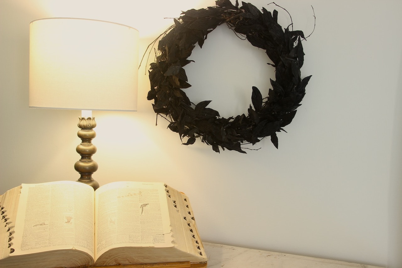 black leaf and grapevine wreath and giant encyclopedia open to the word macabre