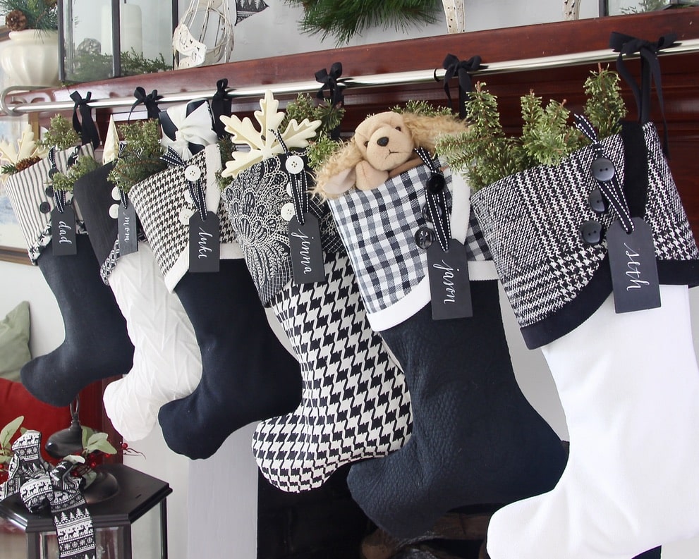 six Black and white Christmas Stockings hanging at an angle with black wood name tags