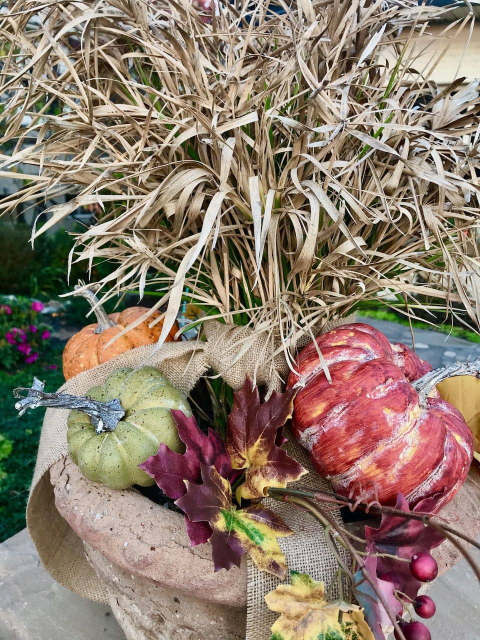 view from above of three different colored pumpkins with faux fall leaves and berries tucked in for filler