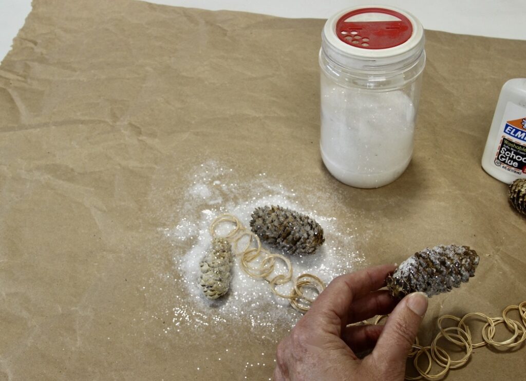 Rolling pinecones in glitter