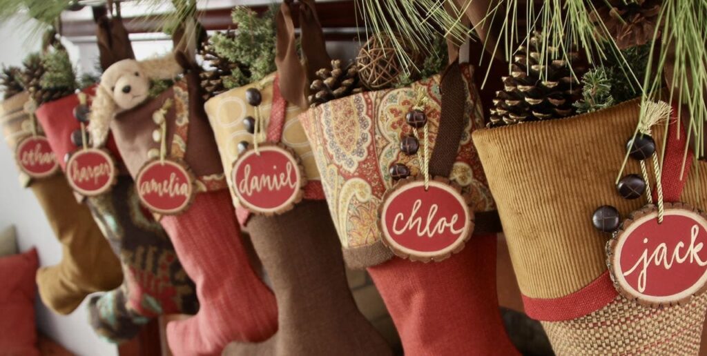 seven coordinating stockings hanging from a mantel with gold-tipped pinecones peeking out of the tops.