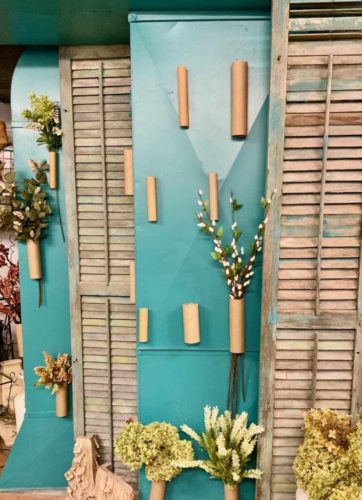 Turquoise HVAC unit with antique shutters and cardboard tubes waiting for all the flowers