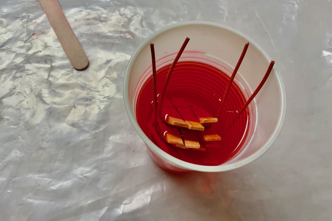 six clothespins on wire floating in cup of dye