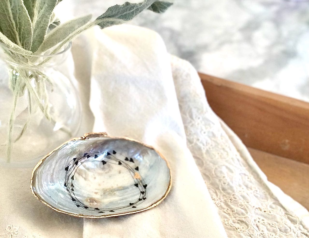 One shell ring dish on linen napkin on wood tray