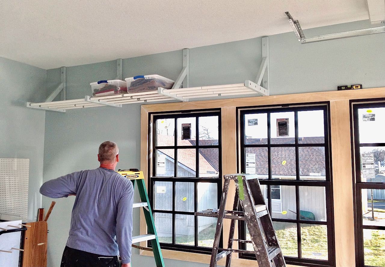 Garage windows with man working on installing overhead storage rack