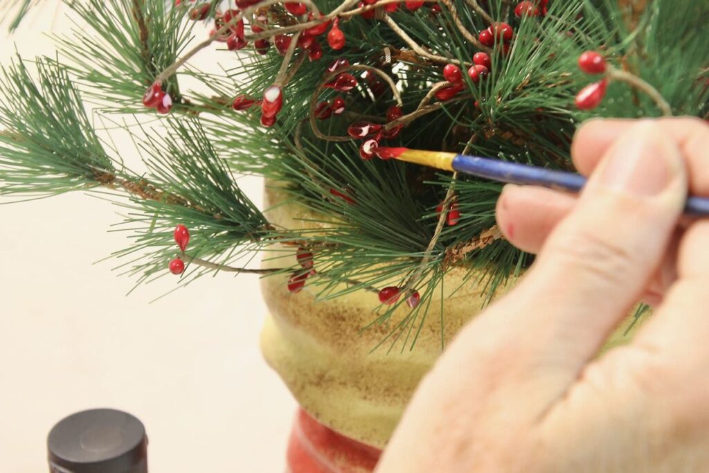 hand holding artist brush to damaged part of berry