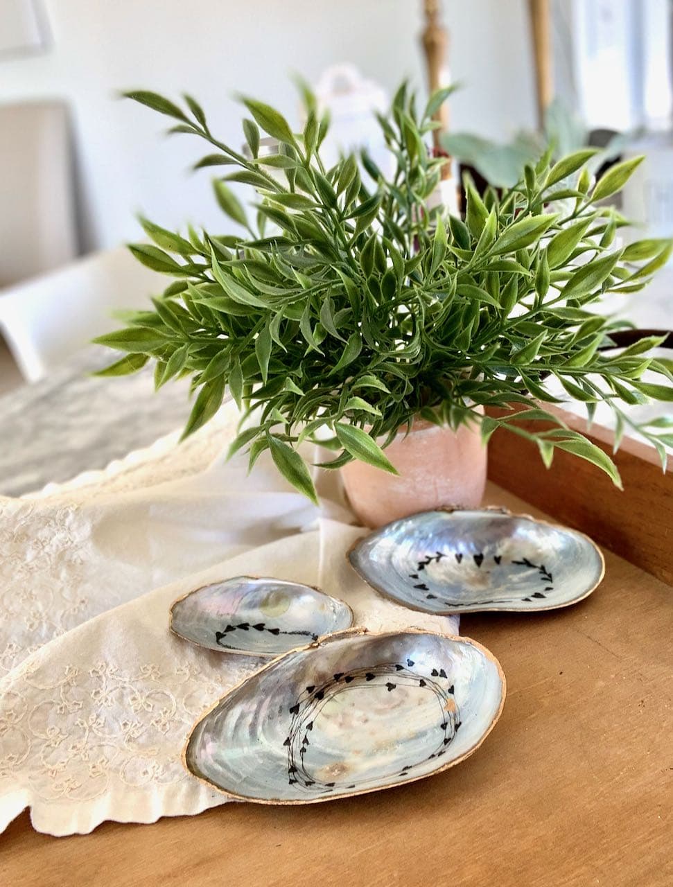 three shell ring dishes on a linen napkin on wood tray on grey marble counter