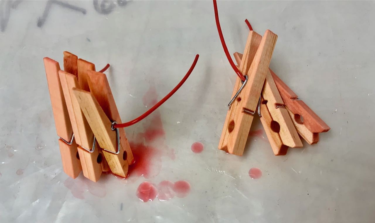 Two sets of three clothespins drying on a plastic cloth
