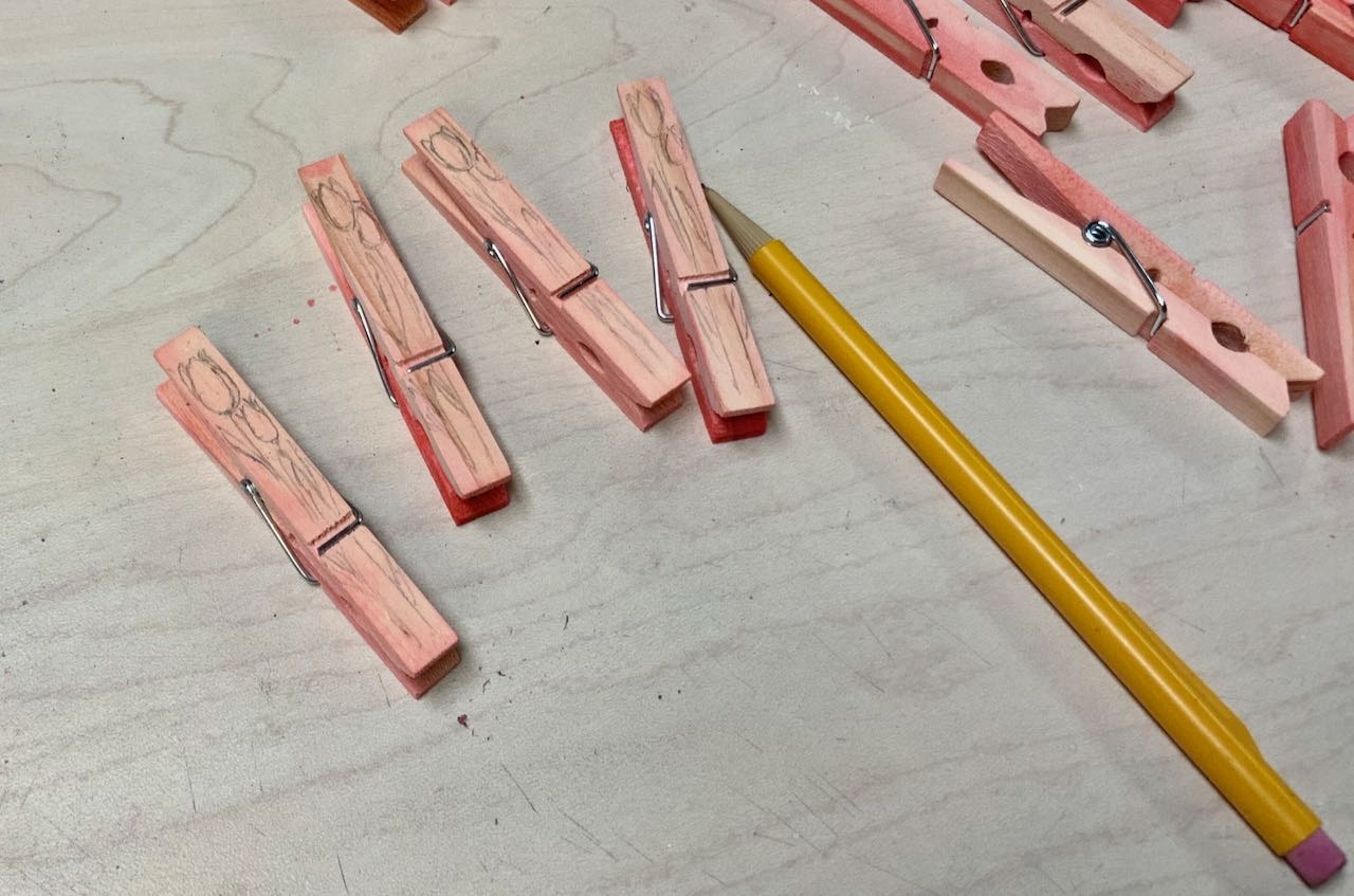 Four dyed clothespins with tulips sketched on them