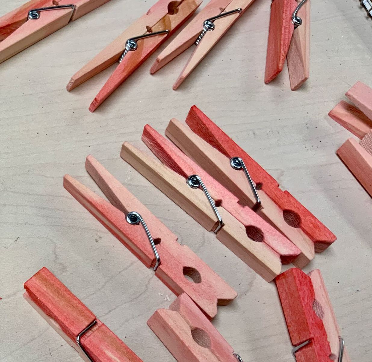 A bunch of dried, dyed clothespins laying on table to show the variation in color to expect