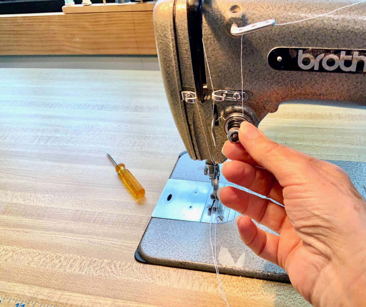 adjusting the tension of the top thread with a knob on the front of a commercial sewing machine