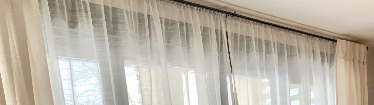 Closeuo view of sheer curtains on a long black rod
