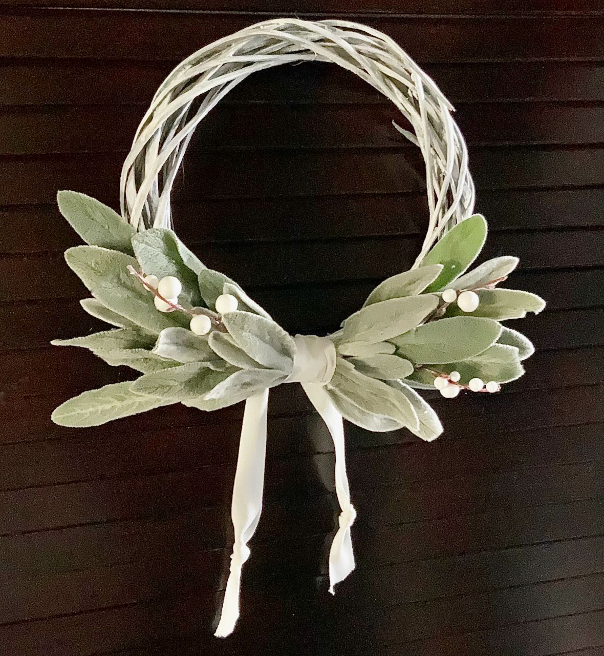 Wreath with lambs ear bundles facing out on the bottom of the wreath with a band of twill and the ends hanging down