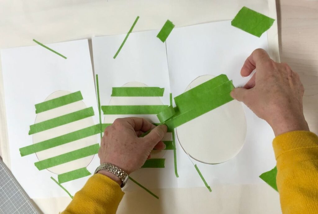 two hands applying the last of three strips of tape side by side