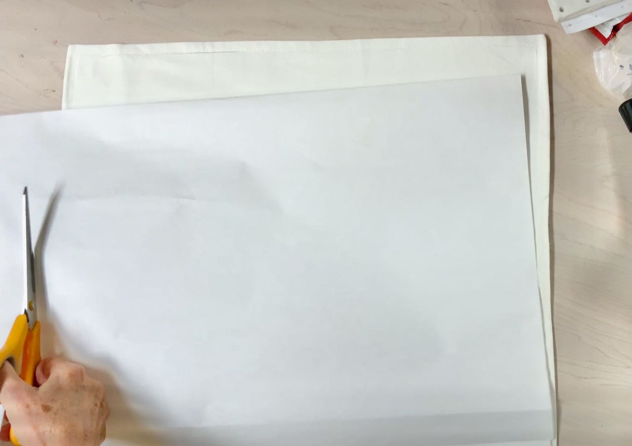 scissors cutting a sheet of paper to fill the pillow slip