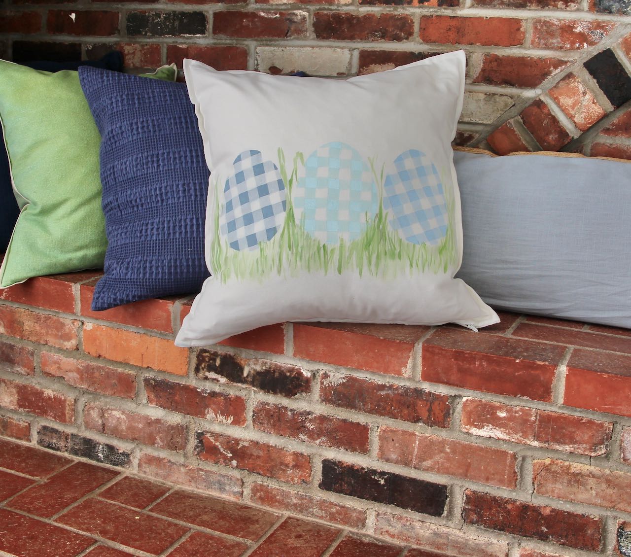 Finished painted pillow on a brick hearth sitting ledge with other solid pillows