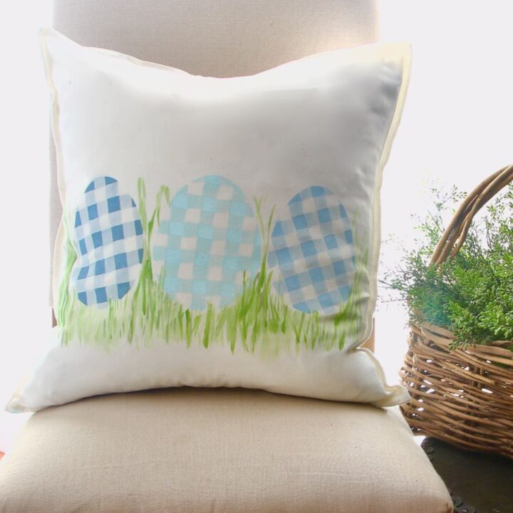 Closeup of pillow with three plaid eggs in tufts of grass