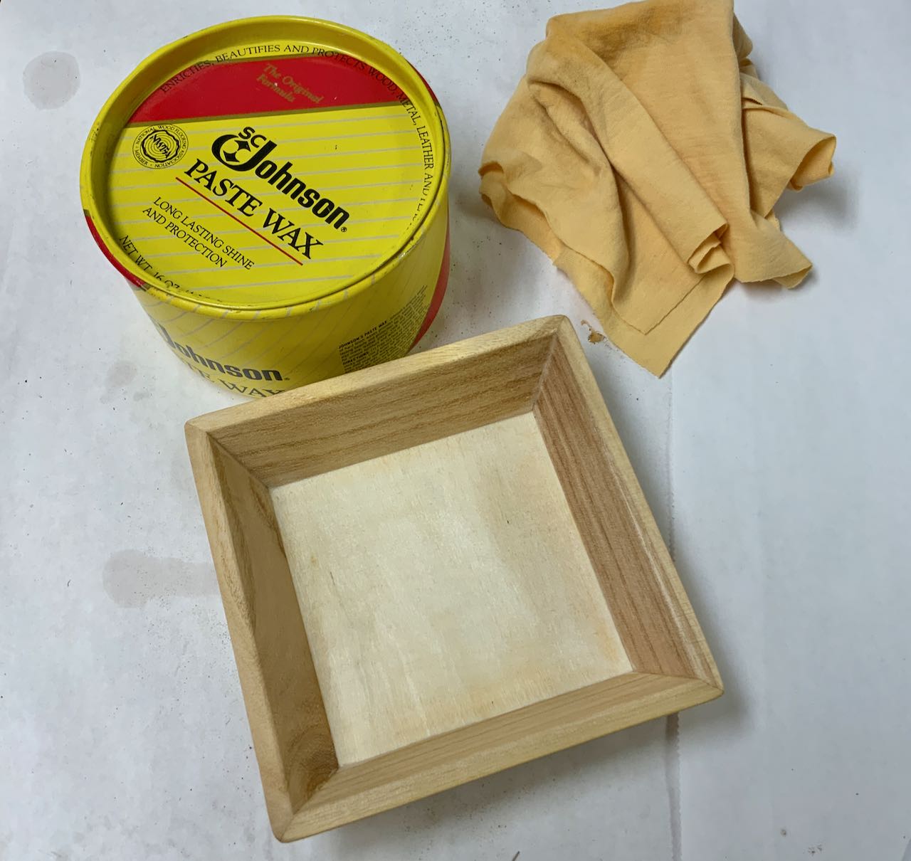 wood box with a sanded and waxed finish with can of wax and rag shown nearby