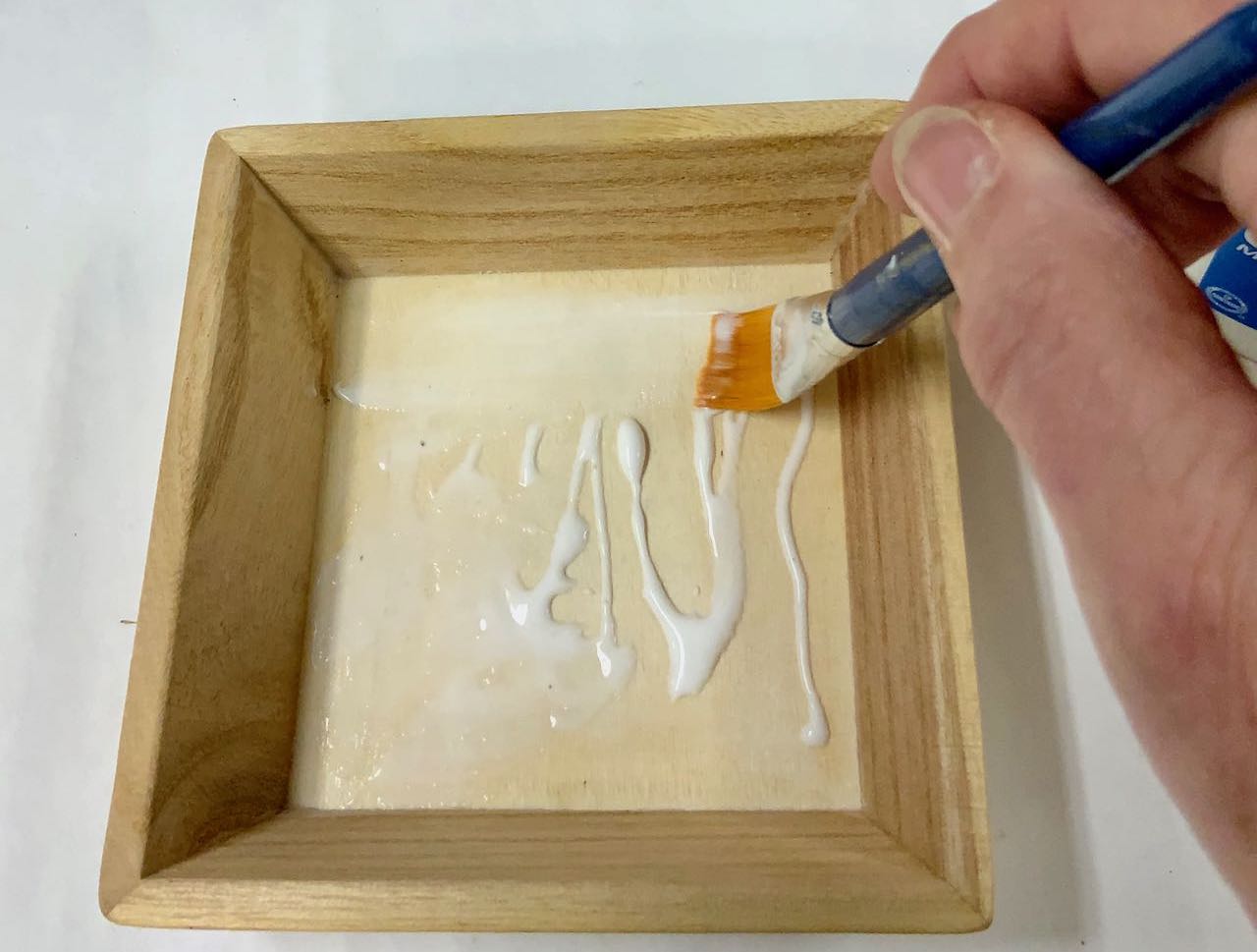 hand spreading glue with paintbrush