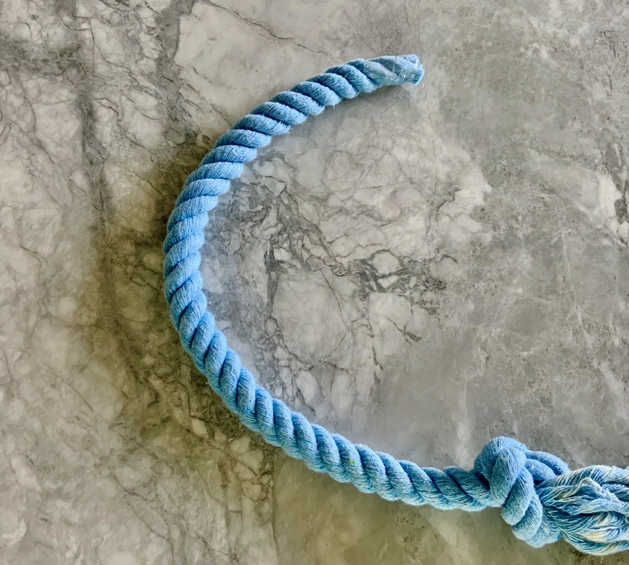 Semicircle of blue dyed rope with tape on one end and a knot on the other