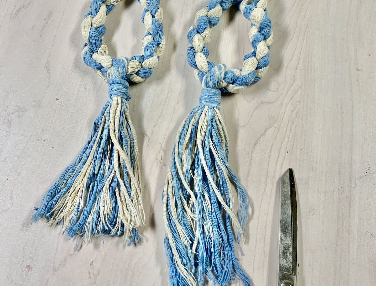 two ties backs with tassels on table showing one trimmed and one not.