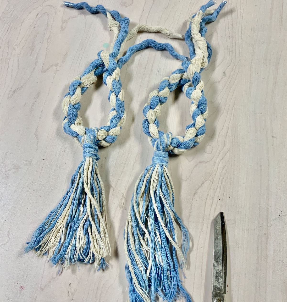 two ties backs with tassels on table showing one trimmed and one not.