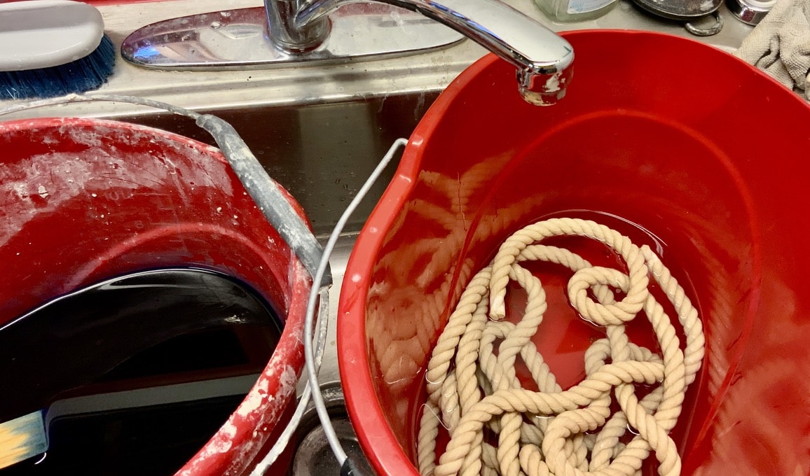 Two buckets, one with dye dissolved in water the other with the natural rope soaking in clear water