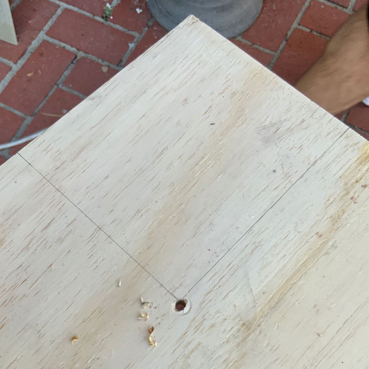 the drawing is shown on the corner of the wood with a hole drilled in the corner where the lines meet