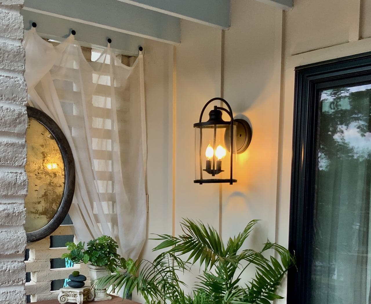 Modern Lantern light fixture on wall and reflected in mirror with palm below