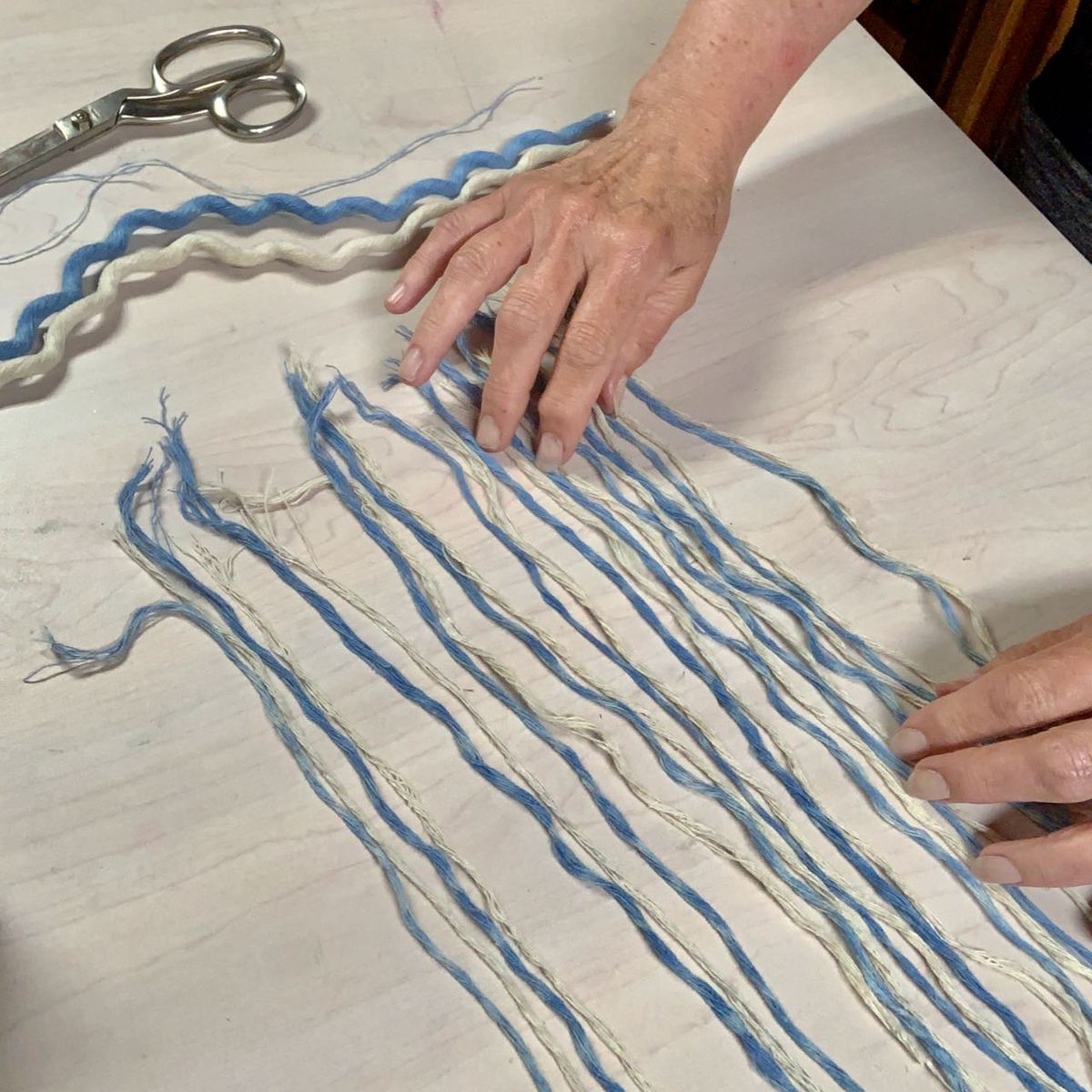 Thin bundles of fibers are laid out on the table in alternating colors