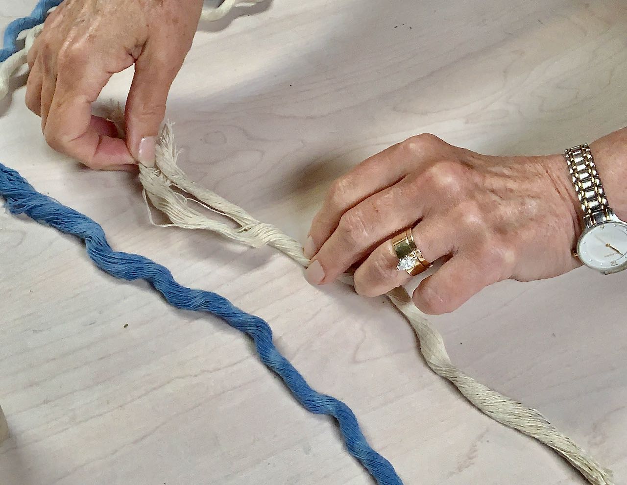 Two hands working at untwisting a bun that made up the original ropedle of the cotton fibers