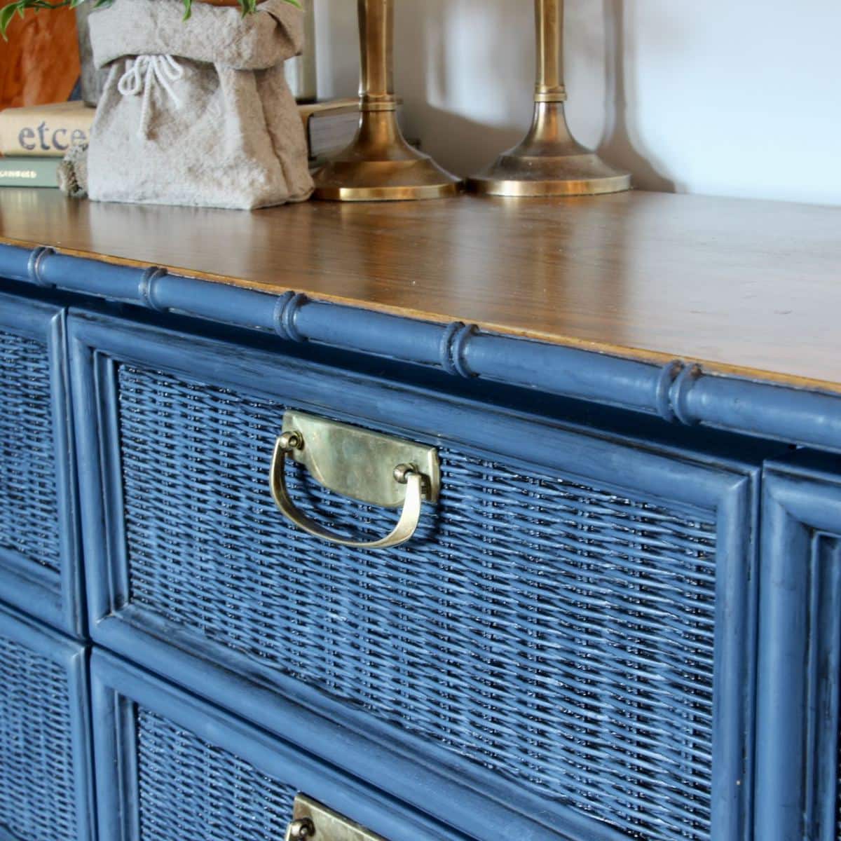 closeup of a wicker drawer painted blue and then glazed with black, the shiny brass handle and the brown wood top