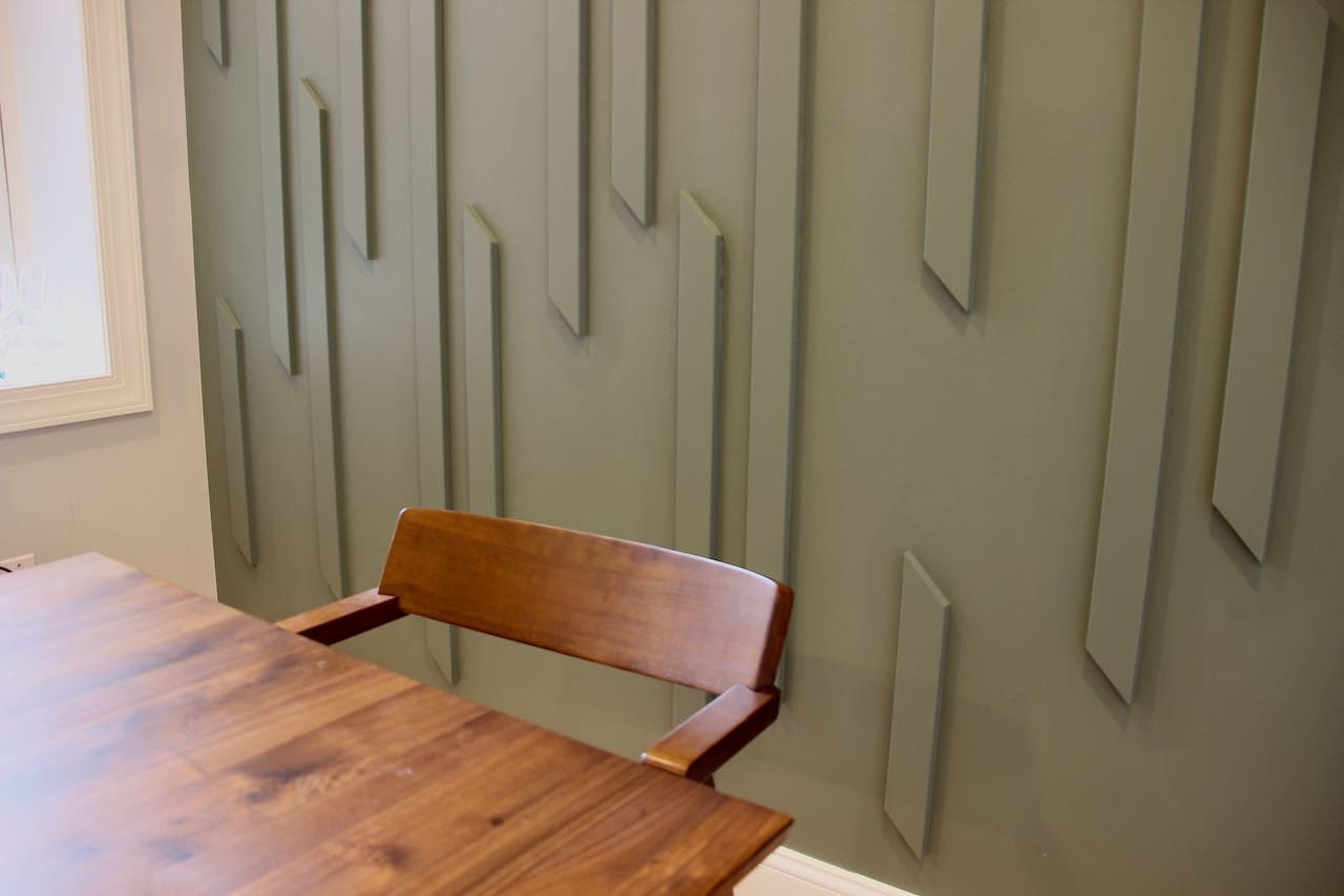 closeup of the feature wall with the dark wood dining table and chair