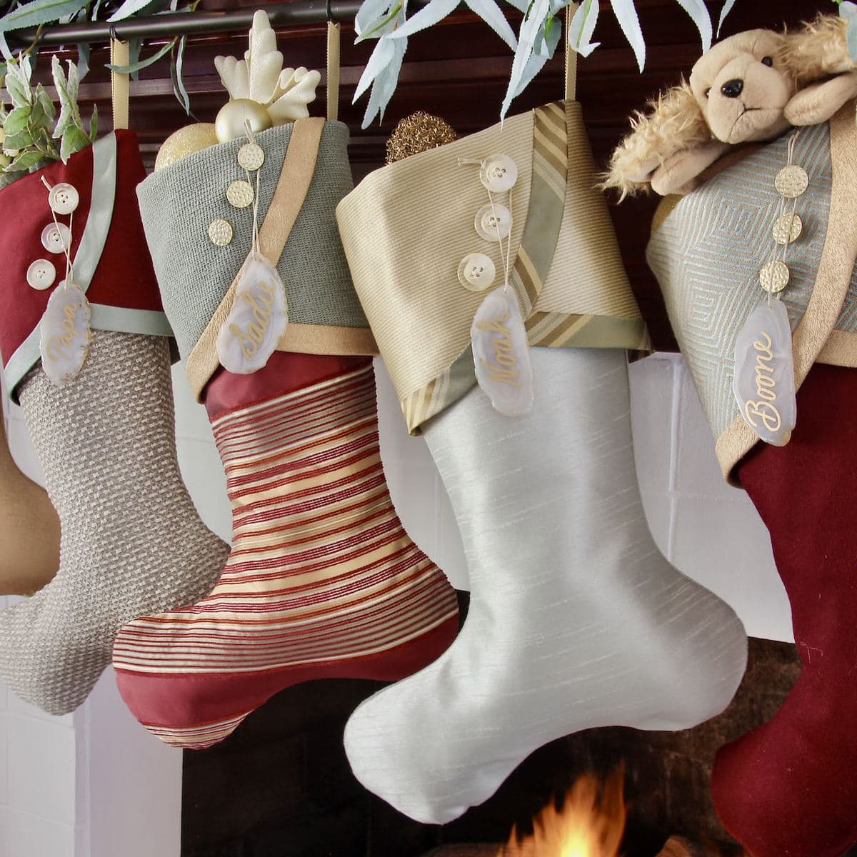 tight image of four burgundy and teal and gold Christmas stockings with names written in on agate slice used for name tags