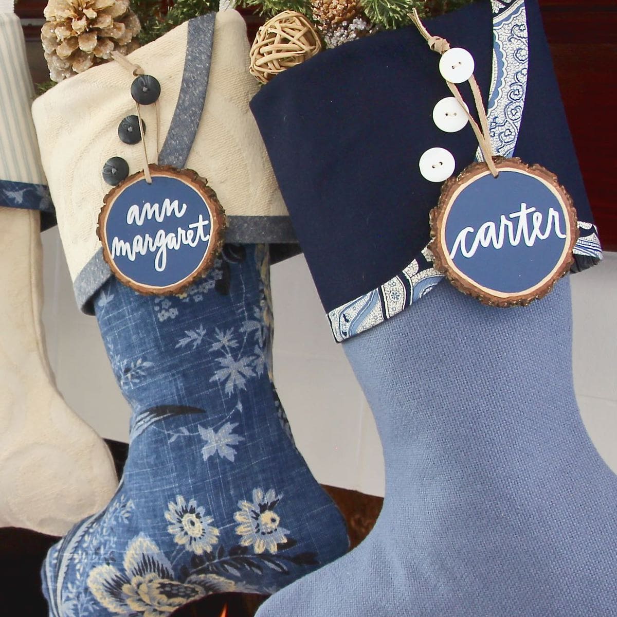 Two Blues Christmas Stockings with Blue and White Tree Slice Name Tags hanging from their cuff buttons