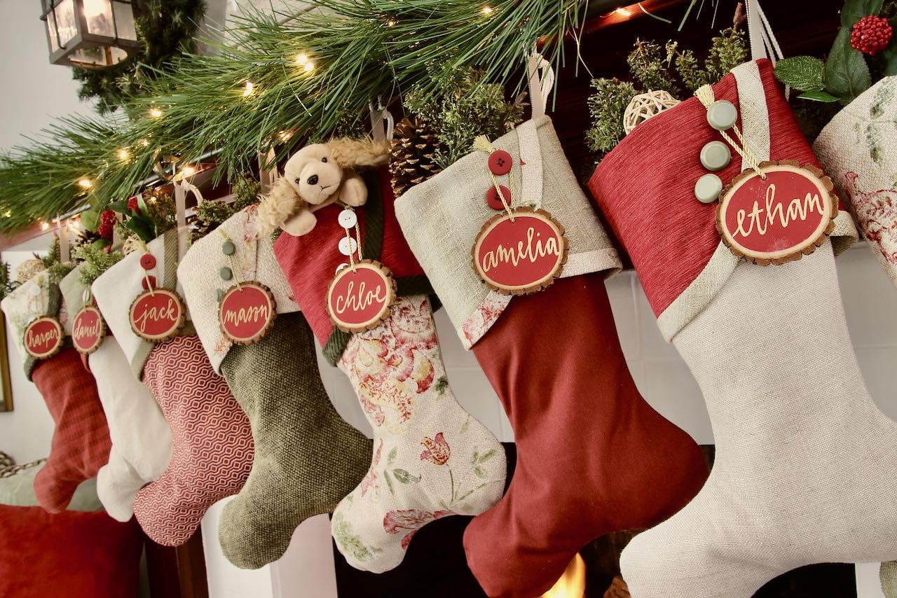 Angle view of 7 Cottage Christmas Stockings with red tree slice name tags